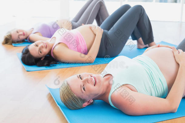 瑜伽课上快乐的孕妇躺在垫子上