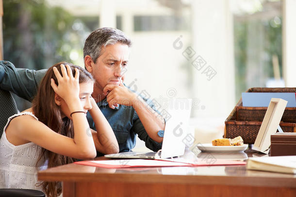 父亲帮助强调十几岁的女儿看笔记本电脑