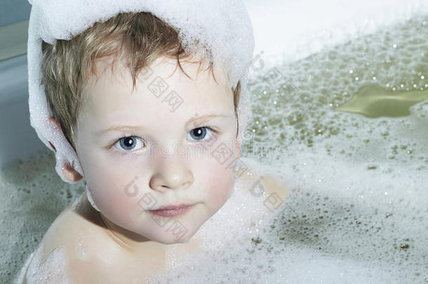 有趣的小男孩在洗澡。古怪的孩子。头上有泡沫
