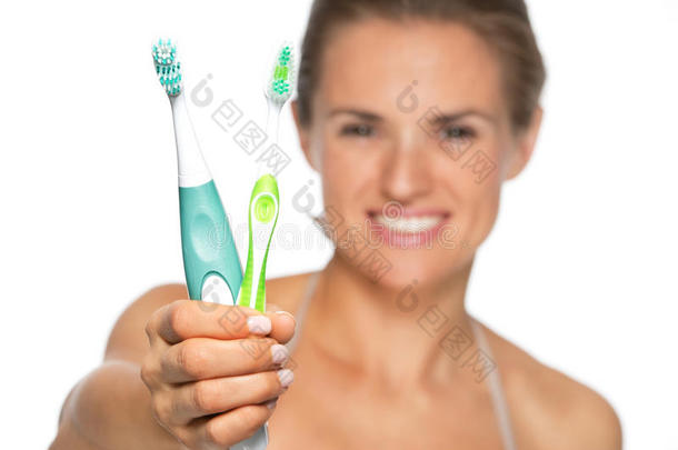 妇女展示旧牙刷和电动牙刷