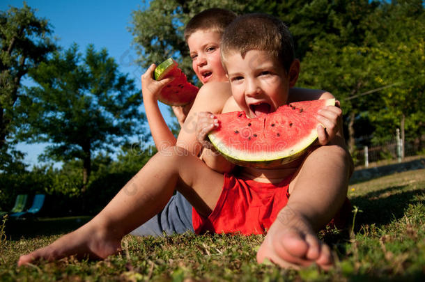 赤膊上阵的孩子在草坪上吃西瓜片