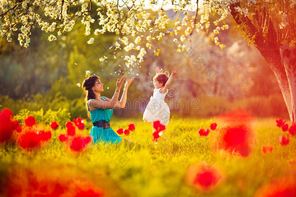 花开的春天里快乐的女人和孩子花园。母亲白天