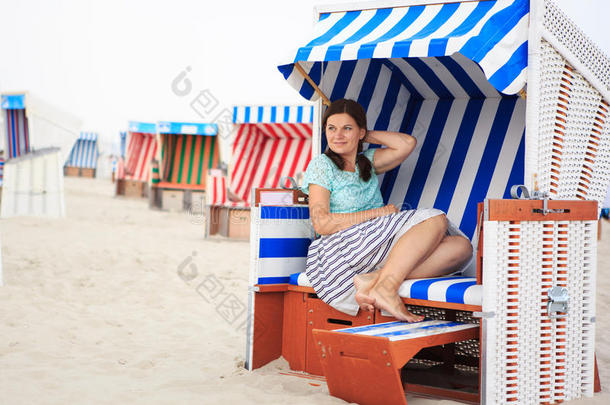 年轻快乐的女人坐在海边的沙滩椅上<strong>放</strong>松。