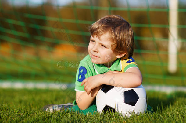 四岁的金发男孩在足球场上踢足球