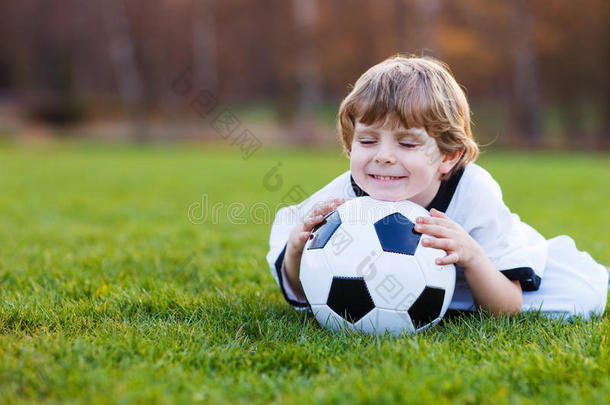 四岁的金发<strong>男孩</strong>在足球场上<strong>踢足球</strong>
