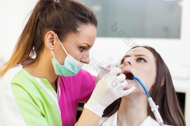 女牙医在为<strong>病人</strong>的牙齿<strong>做手术</strong>