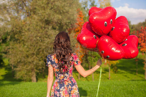<strong>手拿</strong>红色微笑<strong>气球</strong>的年轻女人的后视图
