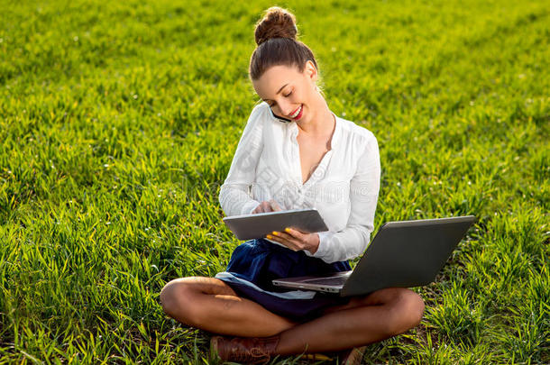 年轻的女人，一个拿着笔记本电脑、平板电脑和绿色手机的女孩