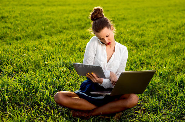 一个年轻的女人在用笔记本电脑、平板电脑和手机工作