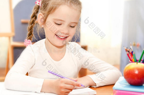 可爱的小女孩在幼儿园的书桌前写字
