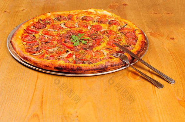 木桌上的意大利香肠披萨配刀叉