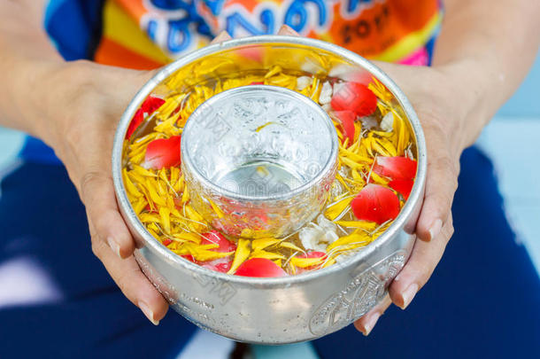 女人手中捧着一碗搀杂着香水和鲜艳花冠的水，泰国泼水节