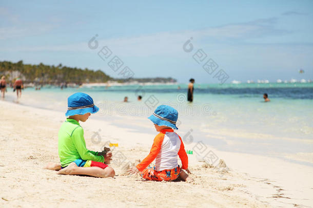 两个白人男孩在热带海滩玩沙子