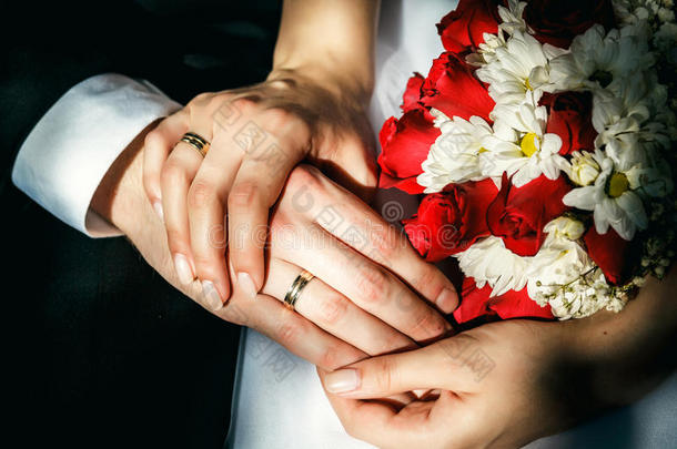 新娘和新郎的手拿着结婚戒指，结婚花束