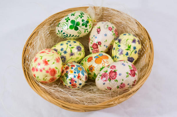 一组彩色复活节彩蛋，用剪纸制作的花朵装饰，放在篮子里