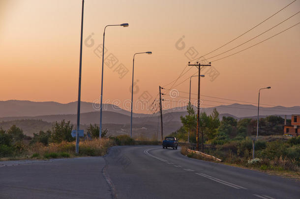 典型的希腊海岸公路，日落时有一辆皮卡车驶过