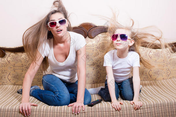 令人惊讶的年轻美女和金发小女孩坐在3D眼镜看3D电影与现实生活的特效