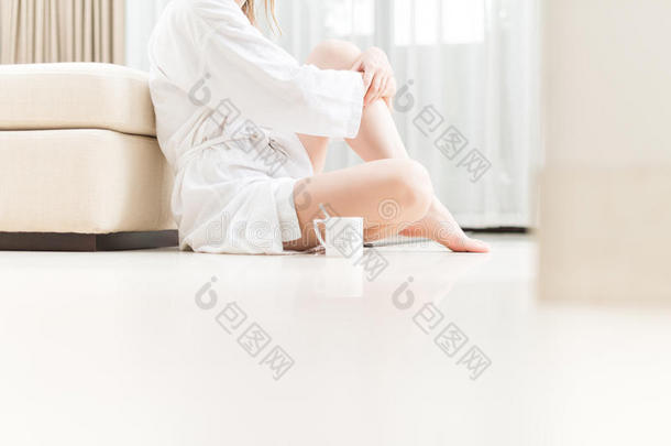 穿着<strong>白色浴袍</strong>的女人坐在地板上。