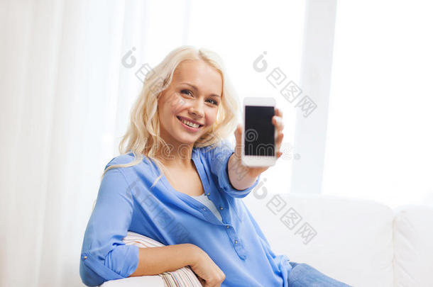 微笑的女人在家里用空白的智能手机屏幕