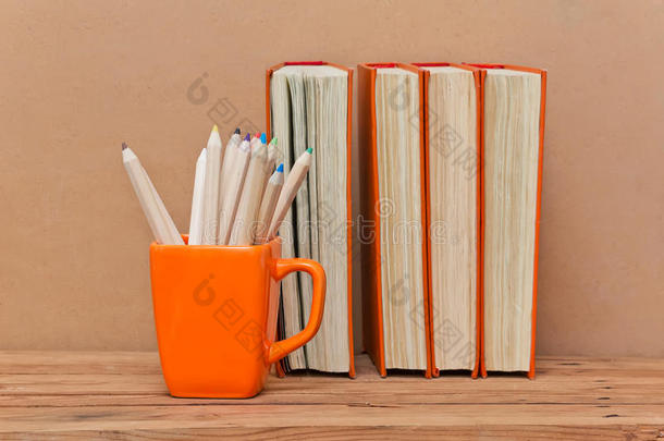 一摞书和一个装有彩色铅笔的杯子