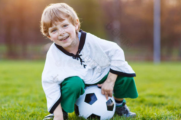 四岁的金发<strong>男孩</strong>在足球场上<strong>踢足球</strong>