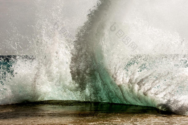 波浪在多石的海滩上破碎，形成一股<strong>浪花</strong>