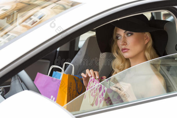 优雅的女孩在车里拎着购物袋