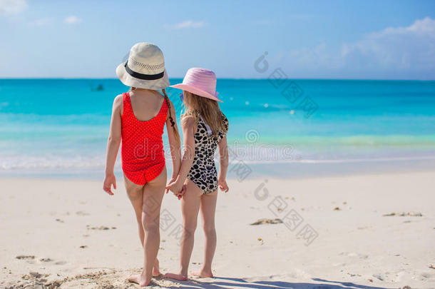 白色海滩上两个小女孩看着大海的背影