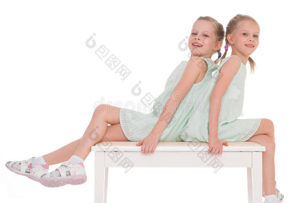 可爱的姐妹们坐在椅子上玩得很开心。