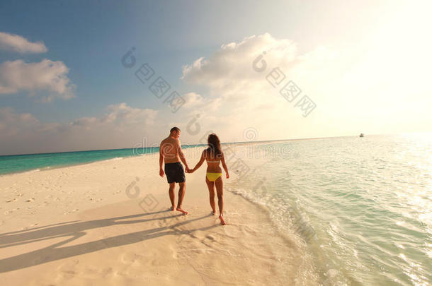 一对情侣漫步在海滩上，夕阳西下，美丽的沙滩