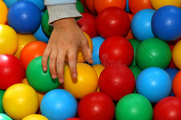 一个带着创可贴的孩子的手拿着彩色的球