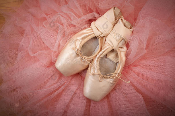 一双芭蕾舞鞋指向木地板