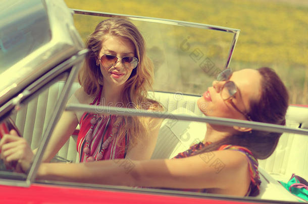 春夏阳光明媚的日子里，戴着太阳眼镜的美女坐在一辆老式汽车里