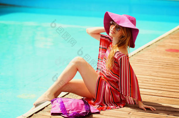 在热带旅游胜地，穿着<strong>比基尼</strong>日光浴的<strong>女士</strong>。美丽的年轻女子躺在游泳池附近的日光浴椅上。