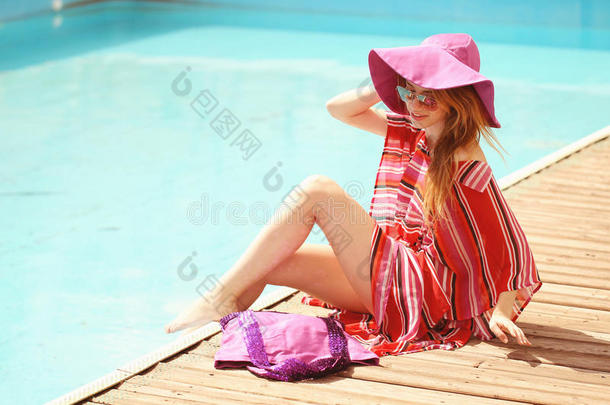 在热带旅游胜地，穿着<strong>比基尼</strong>日光浴的<strong>女士</strong>。美丽的年轻女子躺在游泳池附近的日光浴椅上。