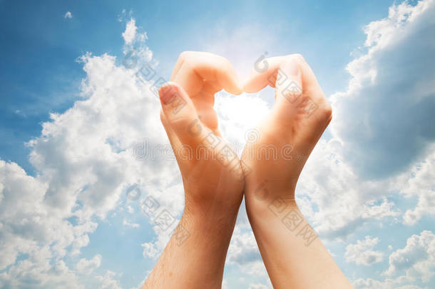 男人和女人的手在晴朗的蓝天上做一颗心。爱