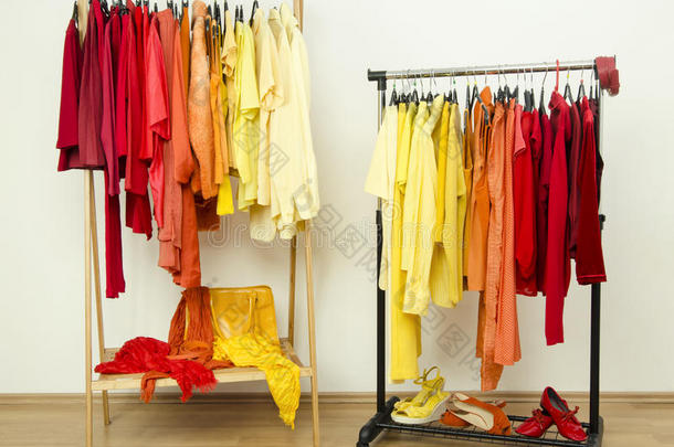 黄色、橙色和红色的<strong>衣服</strong>挂在一个整齐排列的<strong>架子</strong>上。