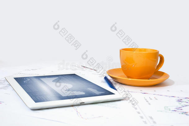 平板电脑、橙色杯子和带图形的纸张