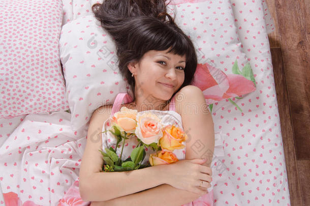 床上的女孩抱着一束玫瑰花