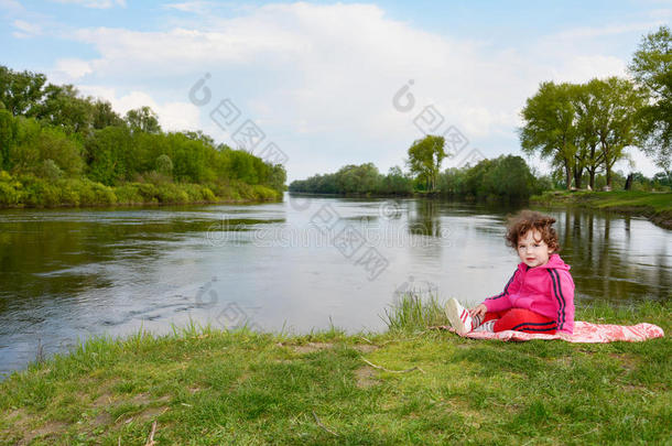坐在河边的小女孩。