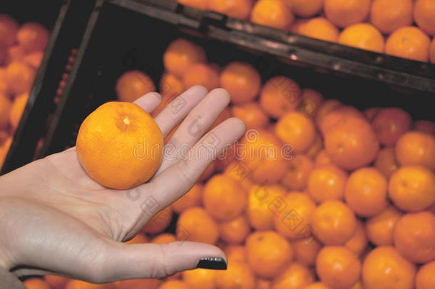 一个女人在蔬菜店里拿着一个橘子