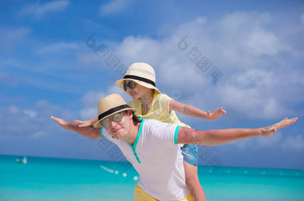 快乐的父亲和他可爱的小女儿在热带海滩玩得很开心
