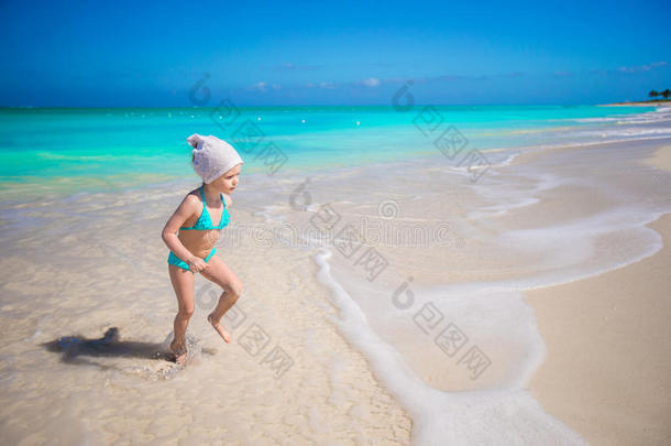 可爱的蹒跚学步的<strong>小女孩</strong>在异国情调的海滩上的浅水中<strong>奔跑</strong>