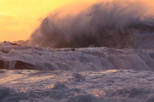 日落时巨大的海浪拍打着岩石