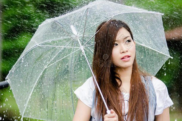 美丽的女孩撑着雨伞站在雨中