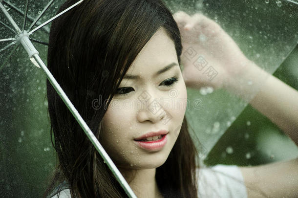 美丽的女孩撑着雨伞站在雨中