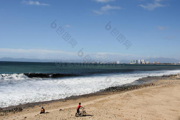 墨西哥海滩上骑自行车的男孩。