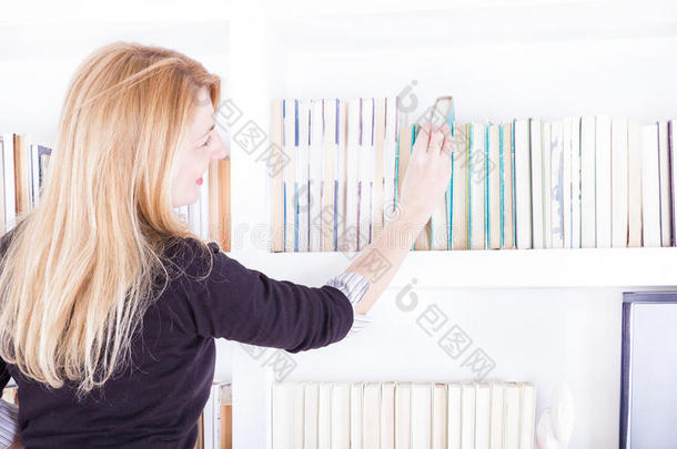 一个金发女人从书架上拿出一本图书馆的书