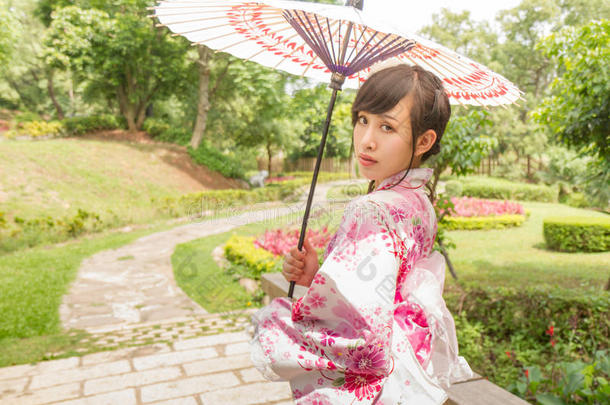 一名亚洲妇女，穿着一个yukata，拿着一把<strong>日语</strong>伞