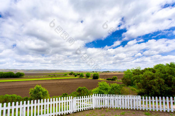 白色的尖桩篱笆，<strong>农田</strong>和云朵